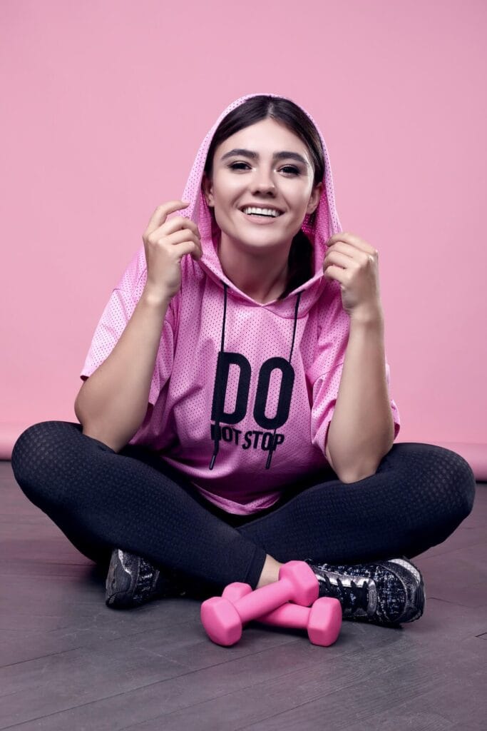 portrait gorgeous body positive latin woman pink sports hoodie exercising with dumbbells pink (1)
